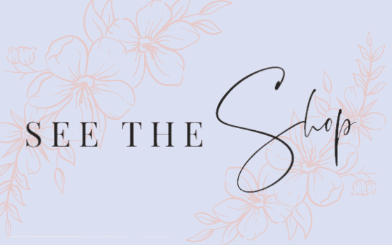 This image is the featured image for the Blog section of the Website. It is a light blue background with pink flowers and a script that says "The Shop"