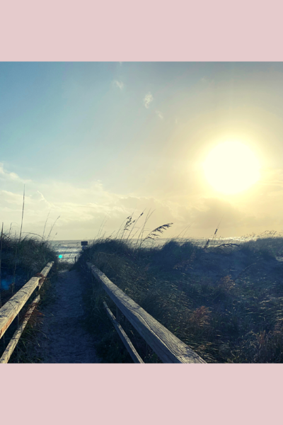 photo of a boardwalk going onto a beach right as the sun is rising.